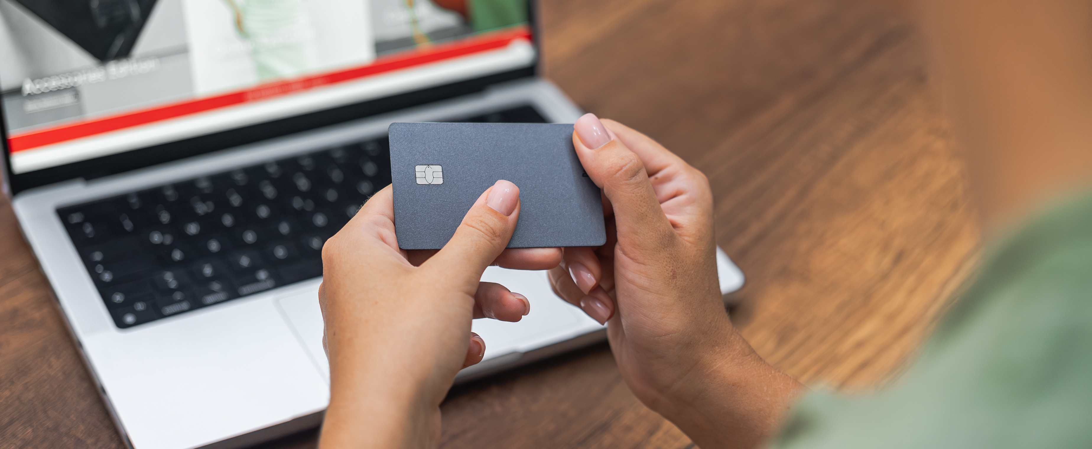 A person holds a credit card in front of an open laptop