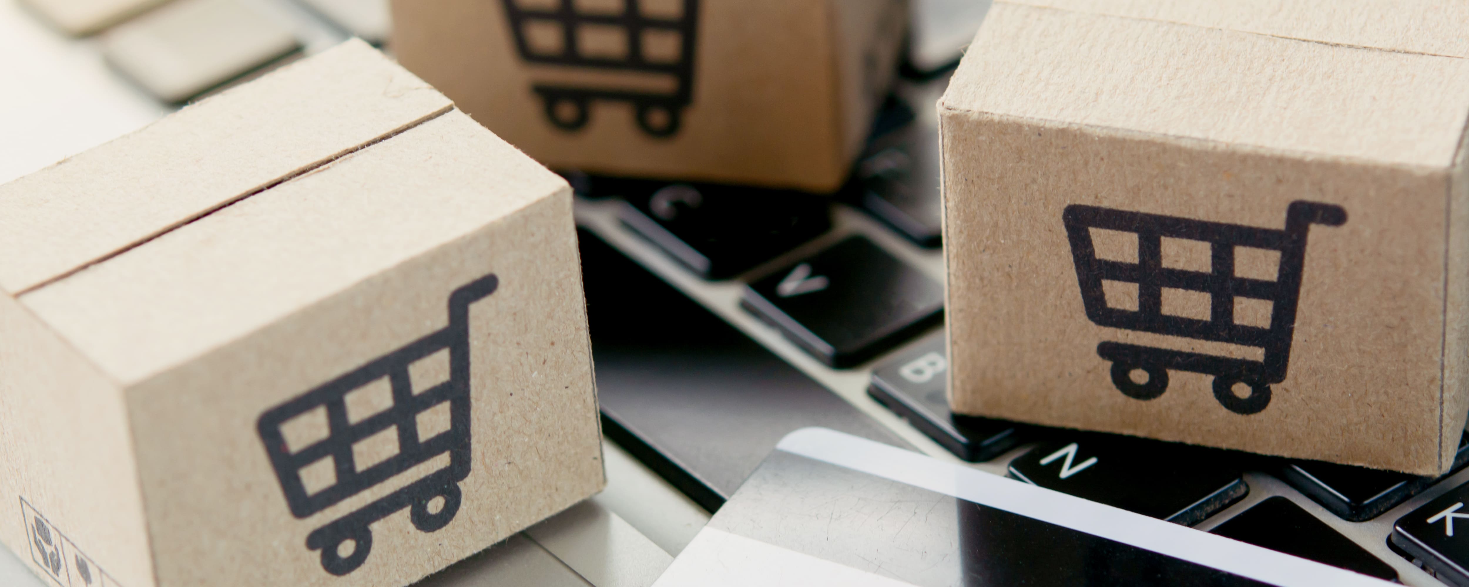 Small cardboard boxes with shopping cart icons sit on a computer keyboard